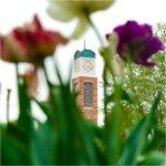 A carillon tower is photographed through colorful purple, pink and white flowers.